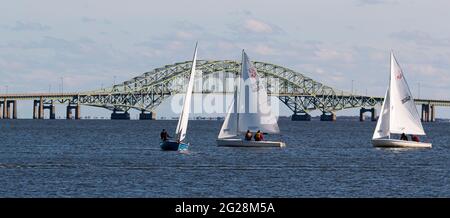 Babylon, New York, USA – 7. Dezember 2019: Kleine Segelboote segeln bei einer Winterregatta mit der Great South Bay Bridge im Hintergrund Stockfoto