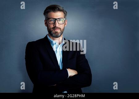 Porträtaufnahme eines gutaussehenden Geschäftsmanns, der die Kamera ansah und lächelte, während er auf einem isolierten grauen Hintergrund stand. Speicherplatz kopieren. Stockfoto