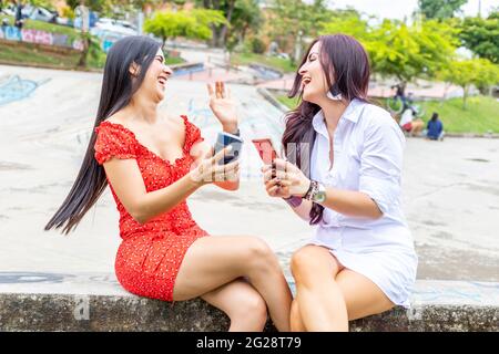 Junge Freundinnen, die Spaß haben und Handy benutzen Stockfoto