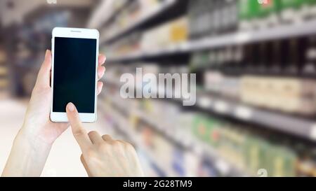 Frau mit smart phon beim Einkaufen im Supermarkt Stockfoto