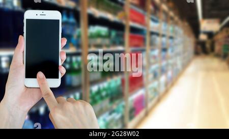 Frau mit smart phon beim Einkaufen im Supermarkt Stockfoto