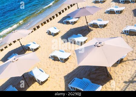 Leere Liegestühle und Sonnenschirme an einem Sandstrand. Stockfoto