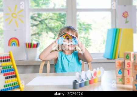 Lustige schöne glücklich Kind Junge zeigt Hände schmutzig mit Farbe. Kind zeichnet lachend mit Farbe. Stockfoto