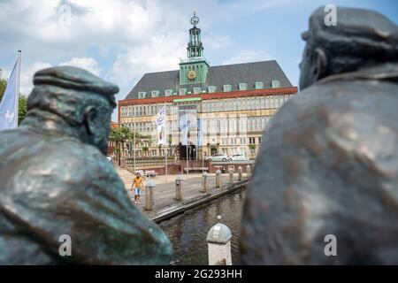 Emden, Deutschland. Juni 2021. Die Figuren 'Delftspucker' stehen auf der Ratsdelft vor dem Rathaus. Nach Wochen mit angespannter Corona-Situation gilt die Stadt Emden ab diesem Freitag (0 Uhr) nicht mehr als hochaktuelle Gemeinde. Die Hafenstadt in Ostfriesland blieb am Mittwoch zum fünften Mal in Folge unter einer siebentägigen Inzidenz von 100 Tagen, so der stadtrat. Daher soll die Ausgangssperre, die in der sogenannten Bundesnotbremse festgelegt wurde, ab Freitag aufgehoben werden. Quelle: Sina Schuldt/dpa/Alamy Live News Stockfoto