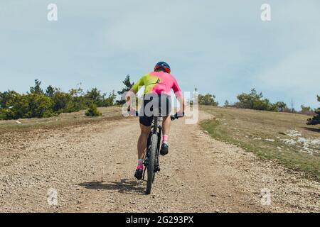 Zurück männlicher Athlet auf dem Mountainbike, der auf dem Trail bergauf fährt Stockfoto