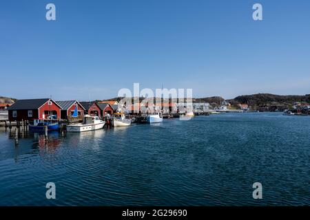 17. April 2021 - Hamburgsund, Schweden: Ein malerisches Fischerdorf an der schwedischen Westküste. Traditionelle Hütten am Roten Meer und ein blauer Himmel im Hintergrund Stockfoto