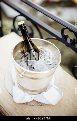 Flasche Champagner im Eimer mit Eiswürfeln auf dem Tisch. Stockfoto