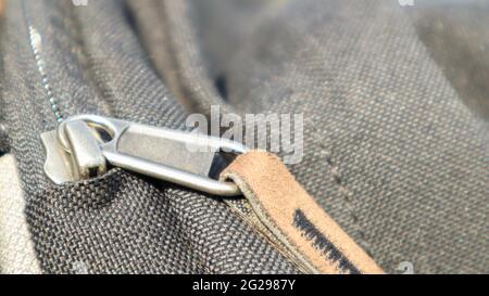Reißverschluss schwarze Tasche Rucksack Textil-Accessoires. Nahaufnahme der Schließe. Textil, Metall und braunes Leder Stockfoto