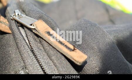 Reißverschluss schwarze Tasche Rucksack Textil-Accessoires. Nahaufnahme der Schließe. Textil, Metall und braunes Leder Stockfoto
