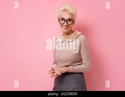 Glückliche Großmutter. Foto von gutherzigen älteren Frau auf rosa Hintergrund. Stockfoto