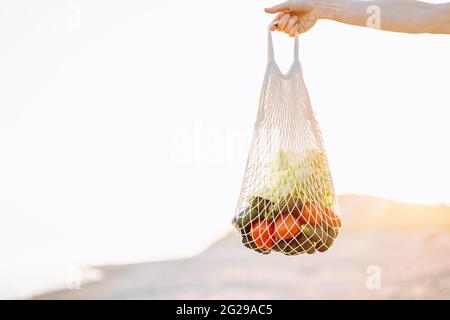 7/8 Schuß von Person, Gelb string Beutel mit frischem Obst und Glasflasche auf Braun Stockfoto