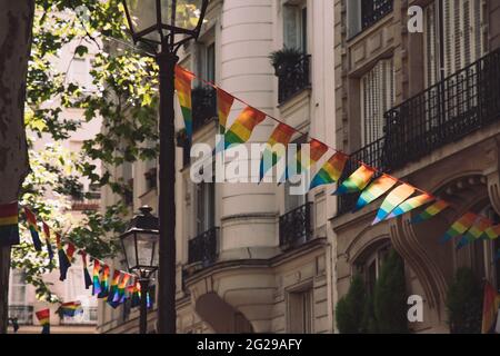 Dekoration von dreieckigen Bannern in LGBTQ-Farben, die zwischen alten Laternen-Straßenlaternen und einem verzierten Steinhaus mit Balkonen hängen. Schwul Stockfoto