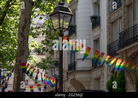 Dekoration von dreieckigen Bannern in LGBTQ-Farben, die zwischen alten Laternen-Straßenlaternen und einem verzierten Steinhaus mit Balkonen hängen. Schwul Stockfoto