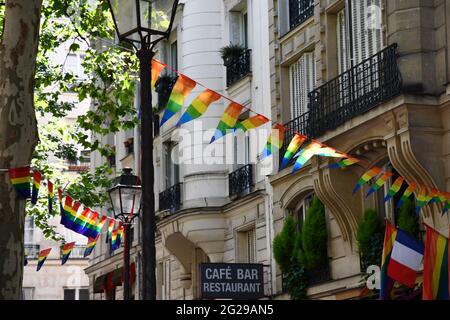 Dekoration von dreieckigen Bannern in LGBTQ-Farben, die zwischen alten Laternen-Straßenlaternen und einem verzierten Steinhaus mit Balkonen hängen. Schwul Stockfoto