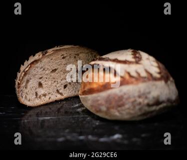 Geschnittener Sauerteig-Boule auf schwarzem Marmor Stockfoto