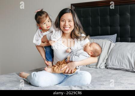 Muttertag. Asiatisch chinesisch glücklich Mutter sitzt spielend auf Bett Stockfoto