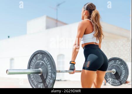 Junge muskulöse europäische Fitness-Frau in schwarzen Shorts, die schwere Deadlift-Übungen im Crossfit-Fitnessstudio macht Stockfoto