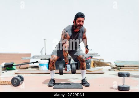 Junger Mann im T-Shirt, der Gewichte im Fitnessstudio hebt Stockfoto