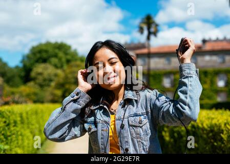 Junge, fröhliche Frau, die im Freien Musik hört und tanzt Stockfoto