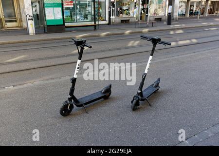 basel schweiz, 24. april. 2021: Zwei weiße Elektroroller auf einem Bürgersteig geparkt, im Schatten ohne Menschen, Elektrofahrzeuge sind sehr beliebt m Stockfoto