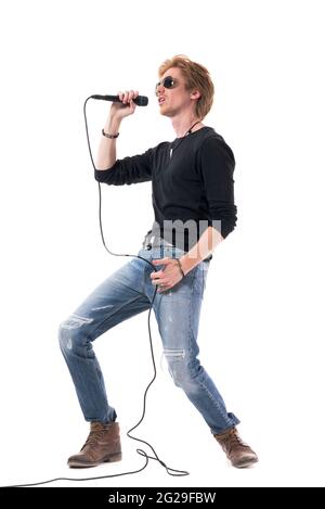 Seitenansicht des energischen leidenschaftlichen Rocker-Sängers, der laut am Mikrofon singt. Ganzkörperlänge isoliert auf weißem Hintergrund. Stockfoto