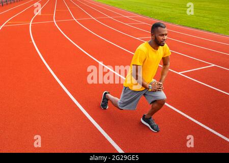 Porträt eines sportlich fokussierten schwarzen Mannes in Sportkleidung, der sich vor dem Training im Freien aufwärmt und gelbe trendige Sportbekleidung trägt.junger Afro-Amerikaner Stockfoto