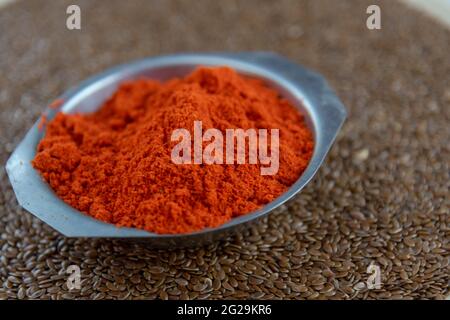 Kulinarische Würze von Bixa orellana auf Leinsamen. Die Annatto-Würze, auch Paprika genannt, ist in europäischen kulinarischen Rezepten üblich. Gewürze und Seasonin Stockfoto