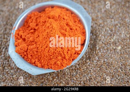 Kulinarische Würze von Bixa orellana auf Leinsamen. Die Annatto-Würze, auch Paprika genannt, ist in europäischen kulinarischen Rezepten üblich. Gewürze und Seasonin Stockfoto