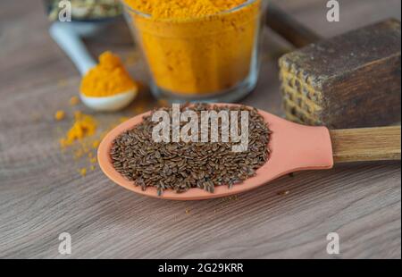 Leinsamen in Silikonlöffel auf Holzhintergrund. Leinsamen ist der Samen von Leinsamen (Linum usitatissimum) und wird beim Kochen verwendet. Gewürze und Gewürze. Stockfoto