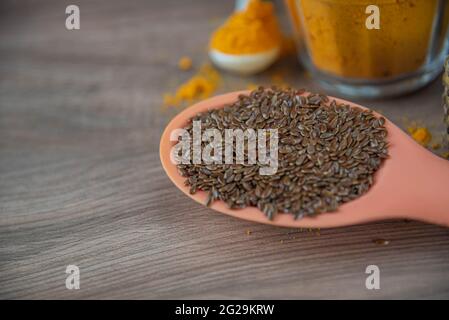 Leinsamen in Silikonlöffel auf Holzhintergrund. Leinsamen ist der Samen von Leinsamen (Linum usitatissimum) und wird beim Kochen verwendet. Gewürze und Gewürze. Stockfoto