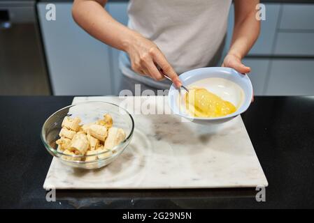 Frau, die Eier für ein Bananenpfannkuchen-Rezept hastert Stockfoto