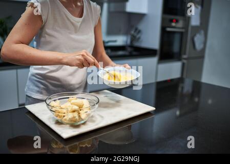 Frau, die Eier für ein Bananenpfannkuchen-Rezept hastert Stockfoto