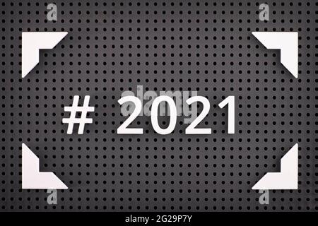 Der Hashtag 2021 wurde mit weißen Zahlen in einem Rahmen auf einem grauen Pegboard geschrieben Stockfoto