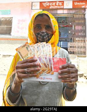 Beawar, Rajasthan, Indien, 9. Juni 2021: Ein Begünstigter zeigt Geld, das sie als COVID-Entlastung von der Regierung von Rajasthan vor einer Bank im Dorf Liri in der Nähe von Beawar erhalten hat. Chief Minister Ashok Gehlot führte Rajasthan Regierung veröffentlicht RS 1000 je für 33 lakh Familien schwer von Coronavirus getroffen. Der Staatsgovt hatte im vergangenen Jahr in drei Raten eine finanzielle Unterstützung von 3,500 Rs an 33 lakh hilflose, mittellose und von COVID-19 betroffene Arbeiterfamilien geleistet. Kredit: Sumit-Samarwat/Alamy Live Nachrichten Stockfoto