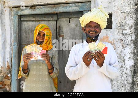 Beawar, Rajasthan, Indien, 9. Juni 2021: Die Begünstigten zeigen Geld, das sie als COVID-Entlastung von der Regierung von Rajasthan vor einer Bank im Dorf Liri in der Nähe von Beawar erhalten haben. Chief Minister Ashok Gehlot führte Rajasthan Regierung veröffentlicht RS 1000 je für 33 lakh Familien schwer von Coronavirus getroffen. Der Staatsgovt hatte im vergangenen Jahr in drei Raten eine finanzielle Unterstützung von 3,500 Rs an 33 lakh hilflose, mittellose und von COVID-19 betroffene Arbeiterfamilien geleistet. Kredit: Sumit-Samarwat/Alamy Live Nachrichten Stockfoto