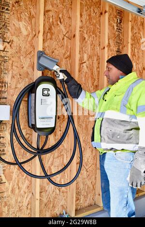 Elektriker installieren Clipper Creek Charger montiert in Garage an privaten Wohnsitz zum Aufladen Tesla Elektrofahrzeuge, Browntown WI, USA Stockfoto