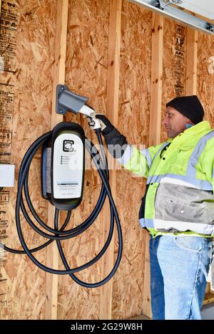 Elektriker installieren Clipper Creek Charger montiert in Garage an privaten Wohnsitz zum Aufladen Tesla Elektrofahrzeuge, Browntown WI, USA Stockfoto