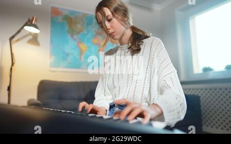 Teenager Mädchen spielen elektronische Musikinstrument zu Hause. Stockfoto