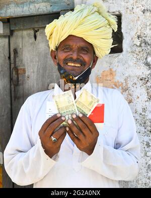 Beawar, Indien. Juni 2021. Ein Begünstigter zeigt Geld, das er als COVID Entlastung von der Regierung von Rajasthan, außerhalb der Union Bank in Liri Dorf in der Nähe von Beawar erhalten. Chief Minister Ashok Gehlot führte Rajasthan Regierung veröffentlicht RS 1000 je für 33 lakh Familien schwer von Coronavirus getroffen. Der Staatsgovt hatte im vergangenen Jahr in drei Raten eine finanzielle Unterstützung von 3,500 Rs an 33 lakh hilflose, mittellose und von COVID-19 betroffene Arbeiterfamilien geleistet. (Foto: Sumit Saleswat/Pacific Press) Quelle: Pacific Press Media Production Corp./Alamy Live News Stockfoto