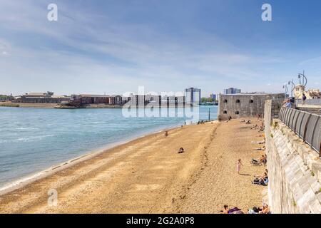 Sonnenanbeter am Kiesstrand genießen die Sonne in Hotwalls, Teil von Point Battery und Barracks in Old Portsmouth, Hampshire, Südküste Englands Stockfoto