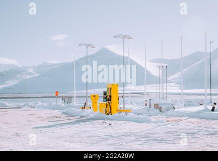 Gelbe Gaspumpe der modernen Tankstelle in der Nähe von verschneiten Bergen am kalten Wintertag in Island Stockfoto