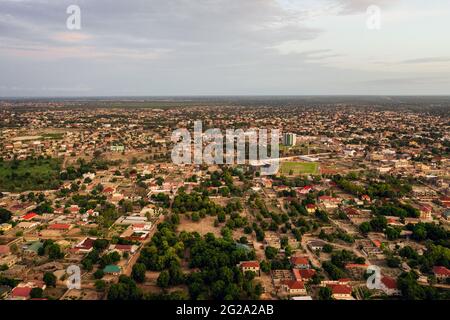 Drohnenansicht von heruntergekommenen Häusern mit viel Grün und staubigen Straßen am Sommertag in Gambia, Afrika Stockfoto
