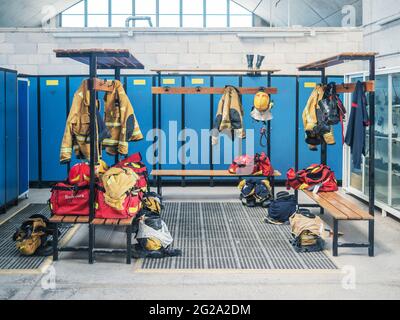 Leerer Umkleideraum in der Feuerwehr mit aufgehängten Uniformen und blauen Schließfächern Stockfoto