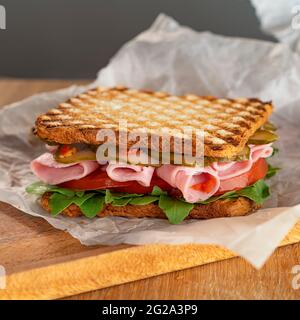 Köstliches Sandwich mit Rucola, Tomaten und Gurken. Frischer Schinken, dünne Scheiben. Ein schneller Snack. Selektiver Fokus. Stockfoto
