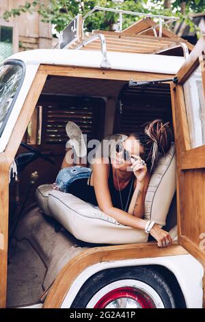 Lächelnde Frau, die auf der Straße in einem Oldtimer liegt Stockfoto