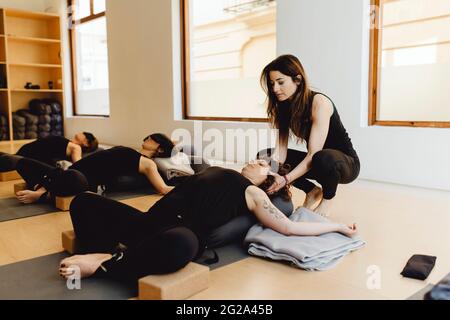 Attraktive junge Yogalehrerin Frau hilft jungen Frauen im Trainingsraum zu entspannen Stockfoto