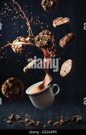 Kreative Studioaufnahme mit Plätzchen, die um einen Schokoladenbecher fliegen Stockfoto
