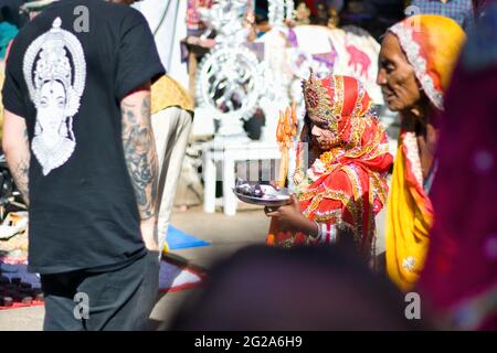 Pushkar, Indien - 10. November 2016: Ein junges Mädchen, das als indische Göttin verkleidet oder verkleidet ist, mit Krone, rotem Kleid und trishul, um Touristen anzuziehen Stockfoto