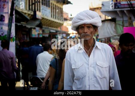 Pushkar, Indien - 10. November 2016: Ein alter Rajasthani-Mann in traditioneller ethnischer Kleidung wie weißem Turban und typischer weißer Kurta, der in einer Straße läuft Stockfoto