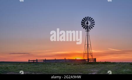 Windmühle mit Wasserpumpe gegen Sonnenaufgang in der Shortgrass-Prärie, Pawnee National Grassland in Colorado Stockfoto